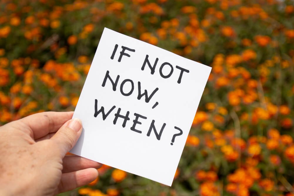 A motivational quote written in bold black letters on a white paper: "If not now, when?"