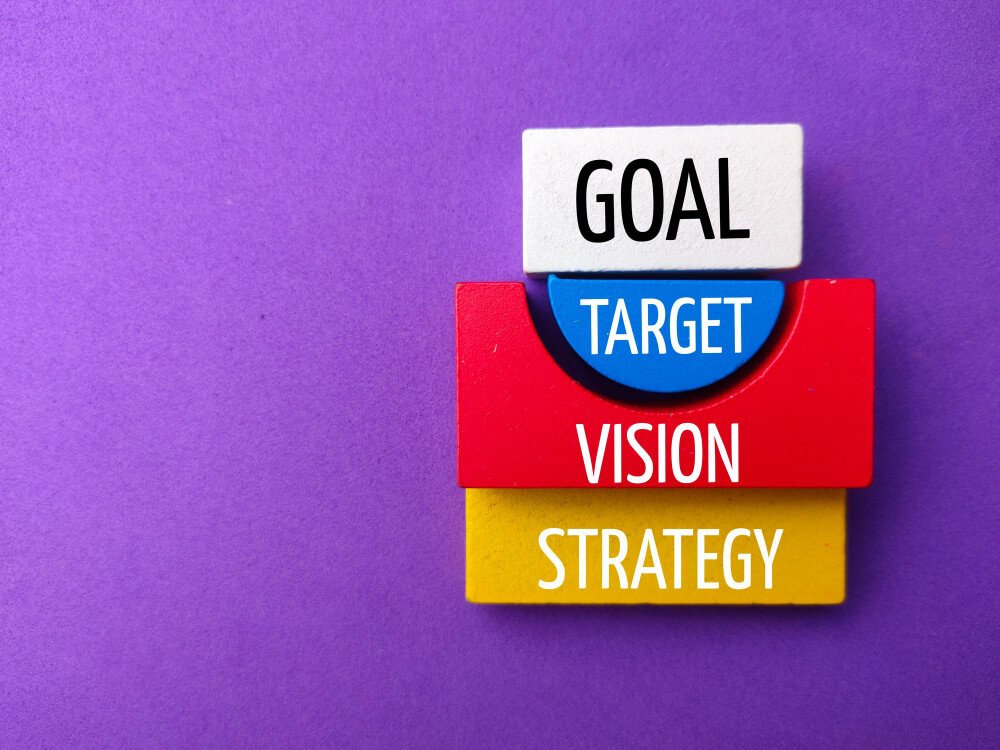 Colorful blocks with words 'goal, target, vision, strategy' stacked together.